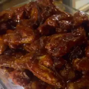A plate of BBQ chicken wings, freshly grilled and coated in a rich, tangy sauce, served hot and ready to enjoy.