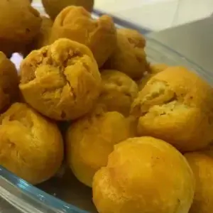 A bowl of golden fried dumplings, crispy and golden brown on the outside, soft and fluffy on the inside, served as a popular Caribbean side.