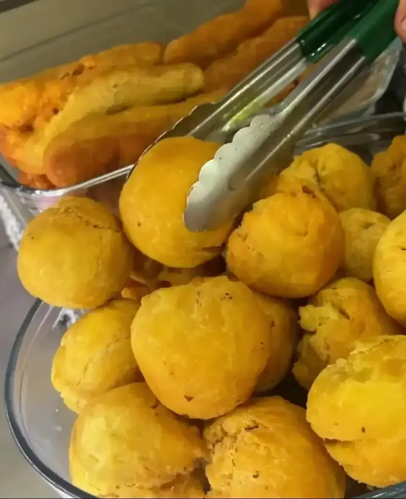 A hand picking up a golden fried dumpling, showcasing the crisp texture and golden brown color of this popular Caribbean snack.